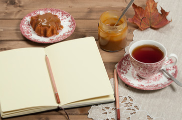 Open Notepad. Homebaked Cake, Maple Leaf Shape. Cup Of Tea. Toffee Sauce. Top View.