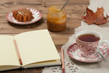 Open Notepad. Homebaked Cake, Maple Leaf Shape. Cup Of Tea. Toffee Sauce. Top View.