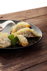A plate of Japanese gyoza dumplings sitting on a rustic wooden t