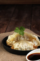 A plate of Japanese gyoza dumplings sitting on a rustic wooden t