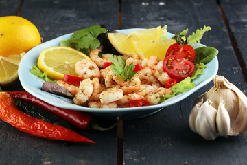 fresh shrimps served on a plate with garlic onion, lemon and chili