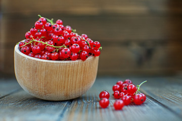 Useful red currants in a wooden bowl. The concept is healthy food, vitamins, diet and vegetarianism.