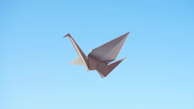 Origami Bird. Flying origami bird on blue background