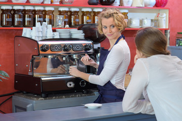 female bartender makes coffee at the bar