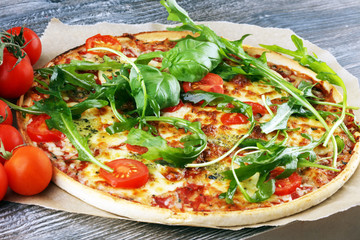 Hot true ITALIAN PIZZA with basil, arugula and cheese. TOP VIEW Tasty traditional pepperoni pizza on board on wooden table with decoration