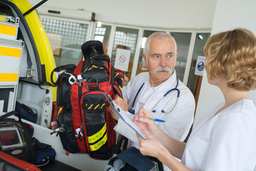 male and female ambulance crew checking their gear before intervention - obrazy, fototapety, plakaty