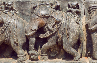 Elephants of Indian architecture background. Traditional style relief, with animals and ancient riders inside the 12th century Hoysaleshwara temple in Halebidu, India.