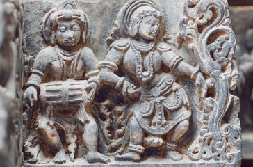 Fototapeta na wymiar Musician with indian drum and lady dancing in traditional style. Stone relief of the 12th century Hindu temple Hoysaleshwara in Halebidu, India