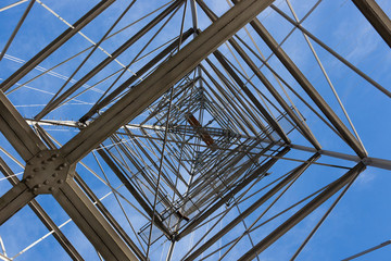 Looking upwards while standing underneath an electrical tower