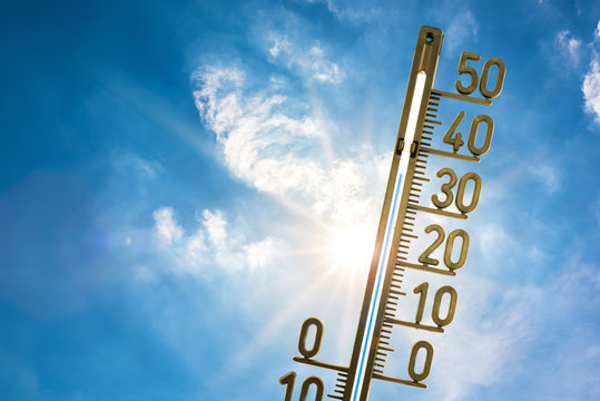 Hitzewelle, Thermometer mit strahlender Sonne und blauem Himmel im Hintergrund