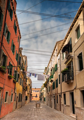 Fototapeta na wymiar View down colourful back street of Venice with many washing lines.