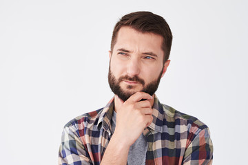 Obraz premium Handsome thoughtful man with beard holding hand on chin looking side thinking about something