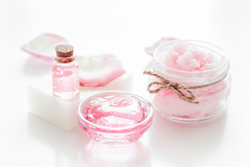 body treatment with rose petals and cosmetic set white desk background