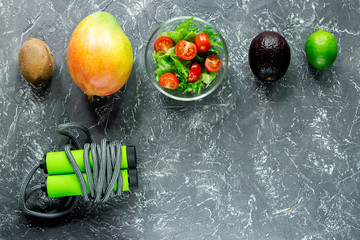 Healthy diet. Salad with fresh products and fruits mango, mangosteen, kiwi and skipping rope on stone table copyspace