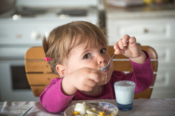 Portrait of little girl eating yogurt with spoon