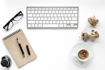 Writer workplace with keyboard, vintage notebook, glasses and coffee on white background top view copyspace