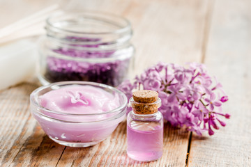 Obraz na płótnie Canvas spa cosmetic set with lilac flowers wooden desk background