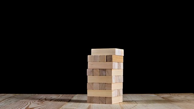 Wooden puzzles jenga gather in tall tower. Stop motion, black background