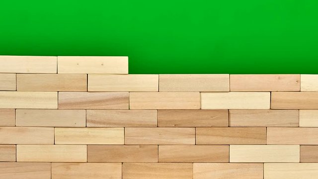 Wooden bricks are gathered into wall. Stop motion, green screen