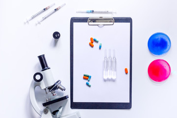 Medical tests. Work table of doctor witn microscope, Petri dish, syringe and ampoule on white background top view