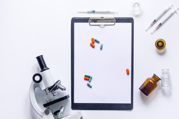 Tools for medical tests microscope and syringe on white background top view copyspace