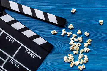 Watching the film. Movie clapperboard and popcorn on blue wooden table background top view