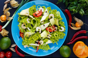 Restaurant food, healthy food, salad, freshness, restaurant menu. Top view on salad with shrimps, caviar and avocado slices on green plate, decorated with chili peppers, lime, herbs and spices