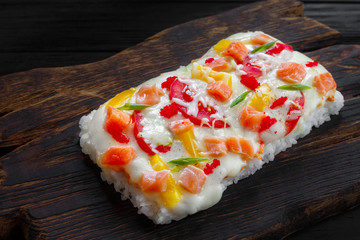 Part of tasty appetizing japanese rice pizza with salmon served on rustic wooden table.Delicious japanese food