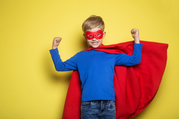 Boy in red super hero cape and mask. Superman. Studio portrait over yellow background