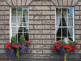 Fototapeta na wymiar Old stone house with colorful window flowers, Edinburgh