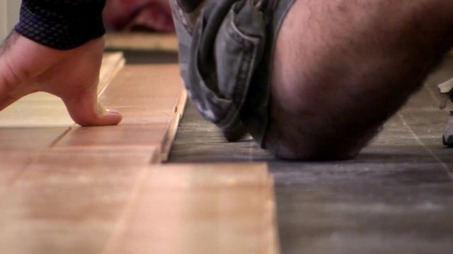 Piece of hardwood flooring is tapped into position with hammer to make nice and tight during floor installation