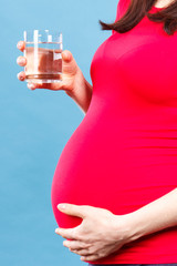 Pregnant woman holding glass of mineral water, concept of healthy lifestyle and hydration in pregnancy