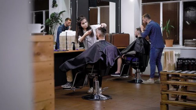The process of hair cutting in barbershop, several hairdressers make stylish and fashionable hairstyles in the men's beauty salon