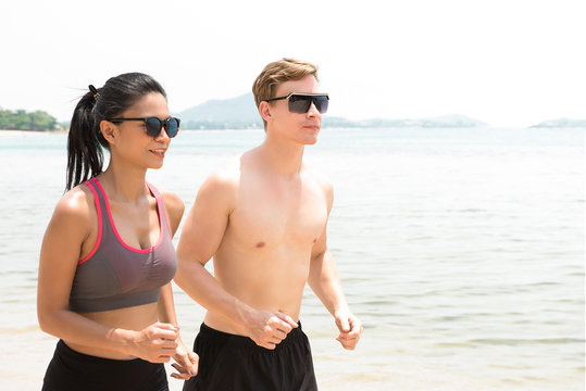 Couple running at the beach in summer - Powered by Adobe