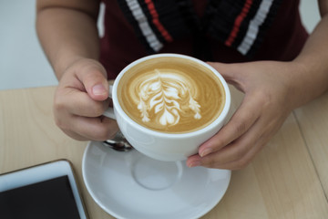 woman holding hot cup of latte coffee