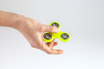 Female hand holding yellow fidget spinner isolated on white background with copy space