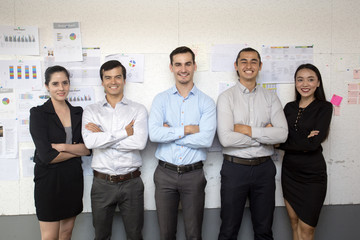 Businesspeople standing together with attractive smiling at working place, business teamwork concept, 5 person.