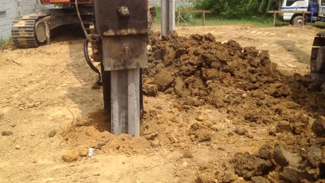 Backhoe with a hammer steel piles device at construction site pile foundation