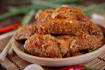 fried chicken wing with herbs in wooden plate and on wooden table