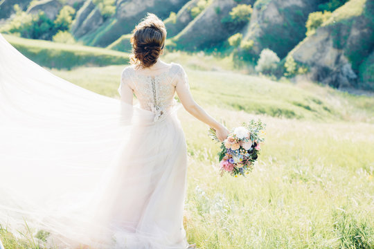 fine art wedding photography. Beautiful bride with bouquet and dress with train in nature