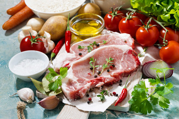 two pieces of pork on a cutting board and fresh ingredients