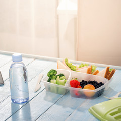 Lunch box with sandwich, vegetables, fruits and bottle of water