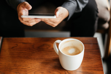 top view. business man holding tablet for checking stock graph. have coffee cup with coffee putting on table front of him. image for beverage,technology,mobile,body part concept