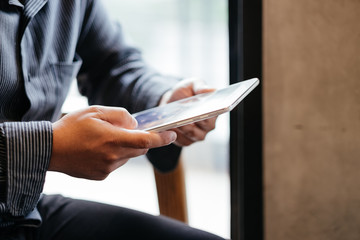 front view. business man holding tablet touch on black screen. sitting at coffee cafe in morning time. image for business,education,mobile,technology,workplace,people concept