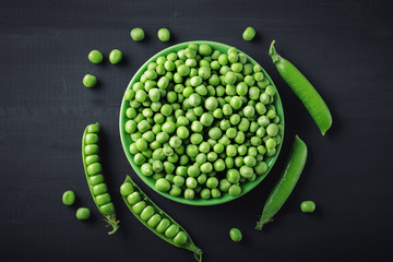 Delicious ripe green peas lying on a wooden table.