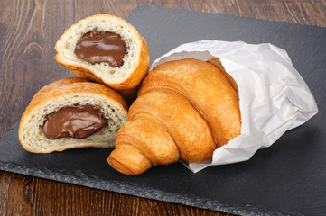 Sliced croissant with chocolate on the background of a slate board.