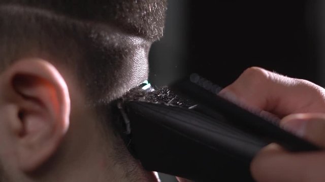 close up shot of the process of cutting hair from a man, the shaving machine gently removes excess hair from the back of the client