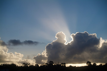 Dramatic sky and horizon with sun rays shining above clouds in New Zealand