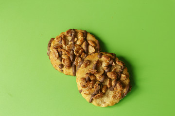 Shortbread, decorated with chocolate glaze and nuts, selective focus, green background