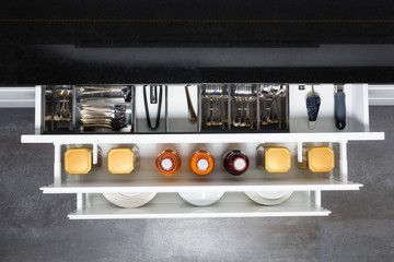 Modern kitchen countertop with food ingredients. Top view of drawers with spices organized inside.